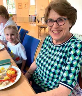 Frau und Kind lächeln an einem Tisch mit Essen.