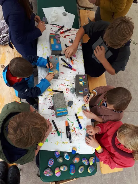 Kinder malen und basteln von oben an einem Tisch.