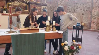 Vier Jugendliche beugen sich über einen Altar und machen Notizen